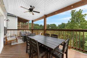 a wooden deck with a dining table and a ceiling fan at Serenity Point Lodge in Branson