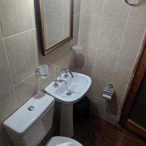 a bathroom with a sink and a toilet and a mirror at Alojamiento Alquiler Temporario in Las Flores