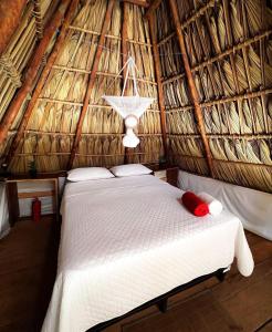 a bedroom with a bed in a thatched room at Macarena Paredon in El Paredón Buena Vista