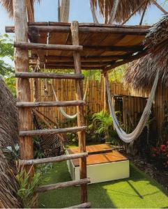 a hammock in a tropical garden with a fence at Macarena Paredon in El Paredón Buena Vista