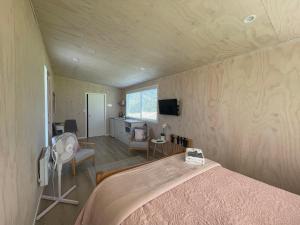 a bedroom with a bed and a room with a tv at Cotman Cottage on Coatesville in Kumeu