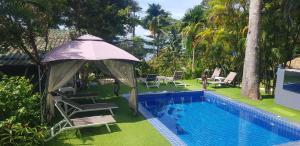 ein Pool mit Stühlen und einem Sonnenschirm neben einem Pool in der Unterkunft COCOON Koh Chang in Ko Chang