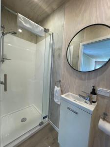 a bathroom with a shower and a sink and a mirror at Cotman Cottage on Coatesville in Kumeu