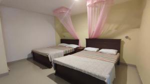 two beds in a small room with pink curtains at Blue Sky in Adams Peak