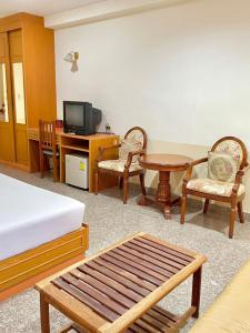 Habitación con cama, mesa y sillas. en โรงแรมเอสซีเรสซิเดนซ์ มุกดาหาร en Mukdahan