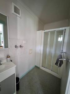 a white bathroom with a shower and a sink at Cottage for two, Marlo in Marlo