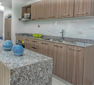 een keuken met marmeren aanrechtbladen en houten kasten bij Elegante apartamento en condominio cerca del aeropuerto 