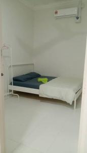 Posto letto in camera con parete bianca di Homestay Taman Tiara Paka Full AC Free Wi-fi & COWAY a Paka