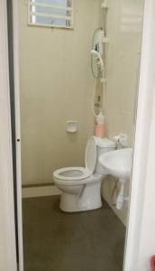 a white bathroom with a toilet and a sink at Homestay Taman Tiara Paka Full AC Free Wi-fi & COWAY in Paka
