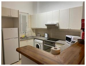 eine Küche mit weißen Geräten und einer hölzernen Arbeitsplatte in der Unterkunft Limnaria Gardens 6464 in Paphos City