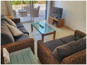 ein Wohnzimmer mit einem Sofa und einem Glastisch in der Unterkunft Limnaria Gardens 6464 in Paphos City