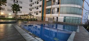 a building with a swimming pool in front of a building at Apartemen Sentraland Semarang in Semarang