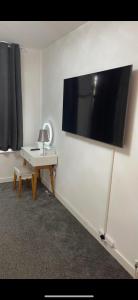 Zimmer mit einem Schreibtisch und einem Flachbild-TV an der Wand in der Unterkunft ARIEL LUXURY APARTMENT in London