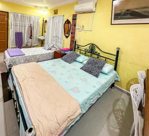 two beds in a room with yellow walls at Dusun Indah Cottage 1 in Bayan Lepas