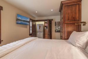 1 dormitorio con 1 cama blanca grande y armario de madera en Luxurious Northstar Condo Walk to Village Shared Hot-Tubs, en Truckee