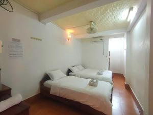 two beds in a room with white walls at phoulisack guesthouse in Ban Sôphoun +18 photos