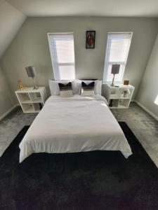 a bedroom with a large white bed with two windows at The Relaxation Oasis in Philadelphia