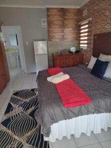 a bedroom with a large bed with a red blanket at Comrades Oasis Guest House in Pietermaritzburg