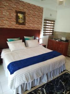 a bedroom with a large bed with blue and white sheets at Comrades Oasis Guest House in Pietermaritzburg