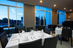 a dining room with white tables and chairs and windows at La Vie En Rose - SHA Plus in Chiang Rai