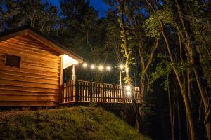 a cabin with lights on the porch at night at Cabane Chalet avec spa privatif in Charnay