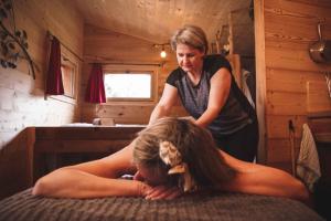 a woman giving a woman lying on a bed at Cabane Chalet avec spa privatif in Charnay