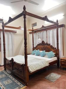 a bedroom with a wooden canopy bed with blue pillows at Amayaa Courtyard Homestay in Hassan