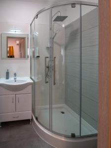 a glass shower in a bathroom with a sink at Levendula vendégház in Szentes