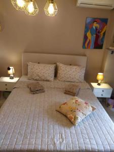 a bedroom with a large bed with two tables and two lamps at Cozy studio, 1min from Kamara in Thessaloniki