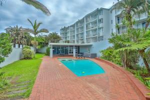 an apartment with a swimming pool in front of a building at Seaside 96 - Family only in Ballito