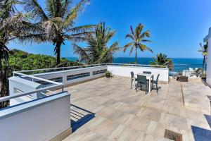 a patio with a table and chairs and the ocean at Seaside 96 - Family only in Ballito