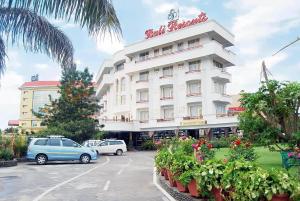 een groot wit gebouw met auto's geparkeerd op een parkeerplaats bij Hotel Bali Resort in Katra