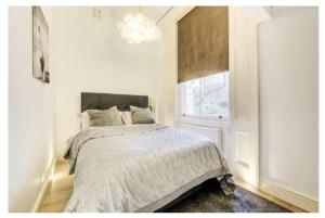 ロンドンにあるStylish Apartment in the heart of Chelseaの白いベッドルーム(ベッド1台、窓付)