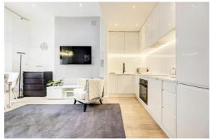 una cocina con armarios blancos y una silla en Stylish Apartment in the heart of Chelsea en Londres