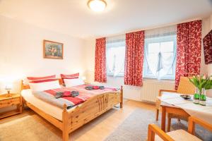 a bedroom with a bed and a table and windows at Pension Haus Anneliese in Ueckeritz