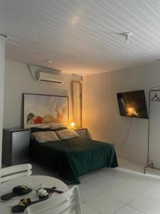a bedroom with a bed and a tv and a table at edf torres ferreira in Lauro de Freitas