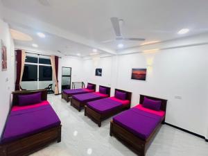 Cette chambre dispose de lits avec des coussins pourpres. dans l'établissement Concey Transit Hotel Airport view, à Katunayake