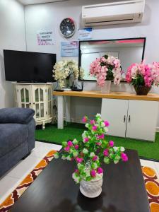 - un salon avec une table et des fleurs dans l'établissement Trails of Kampar Villa Homestay, à Kampar