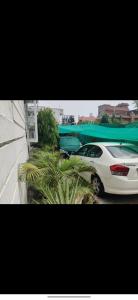 a white car parked next to a building with a green canoe at Simbha's Homestay in Jammu