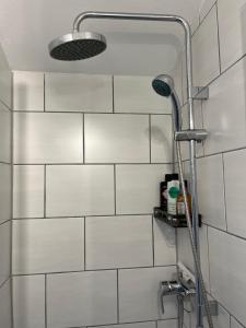 uma cabeça de chuveiro numa casa de banho com azulejos brancos em Ferienwohnung-Weil-Burg em Weilburg