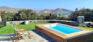 a swimming pool with a deck and a chair in a yard at The old barn, Naousa Paros in Naousa