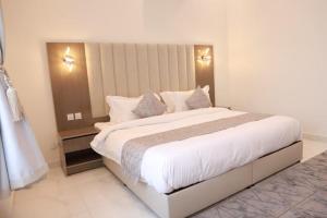 a bedroom with a large bed with white sheets and pillows at شاليهات صن سيت تايم in Khamis Mushayt