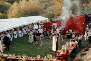 una folla di persone che si aggirano intorno a una tenda con cibo di Lângă Stână a Curtea de Argeş