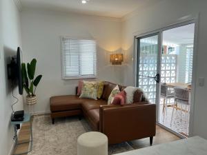 uma sala de estar com um sofá castanho e uma varanda em Modern Pool Oasis & Seaside Abode em Brighton