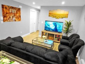 Il comprend un salon doté d'un canapé noir et d'une télévision à écran plat. dans l'établissement Cozy, Comfortable, Convenient - Your Ideal 2BR Stay, à Saskatoon
