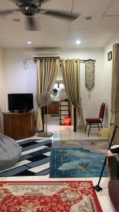 a living room with a couch and a tv and curtains at Berkat Pak Raja Homestay Mergong Alor Setar 