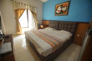 a bedroom with a large bed in a blue room at Pineapple Mansion Guest House Solo in Bonorejo