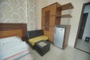a bedroom with a bed and a chair and a refrigerator at Pineapple Mansion Guest House Solo in Bonorejo