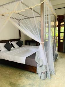 Pearl Gardens Midigama في ميديغاما إيست: غرفة نوم مع سرير مظلة مع ناموسيات