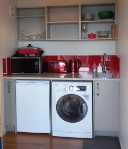 a kitchen with a washing machine and a microwave at Addictive View - Lakeside Studio in Rotorua